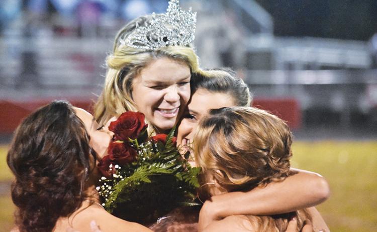 Andrews High School homecoming queen Juliana Aiken hugs fellow seniors (from left) Mariela Jimenez, Sydney Postell and Paige Hooper after getting her crown and roses Friday night.