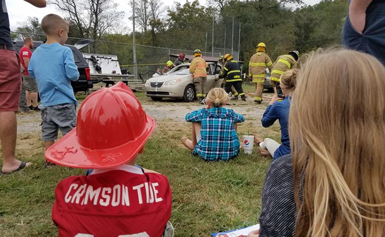 Children watch as teams of volunteer firefighters practice extraction skills and show the difference in tools during the Car Extraction Race at the Ranger Volunteer Fire Department on Saturday. "They're ripping the doors off?" one child exclaimed as the volunteers carefully removed pieces of the car.