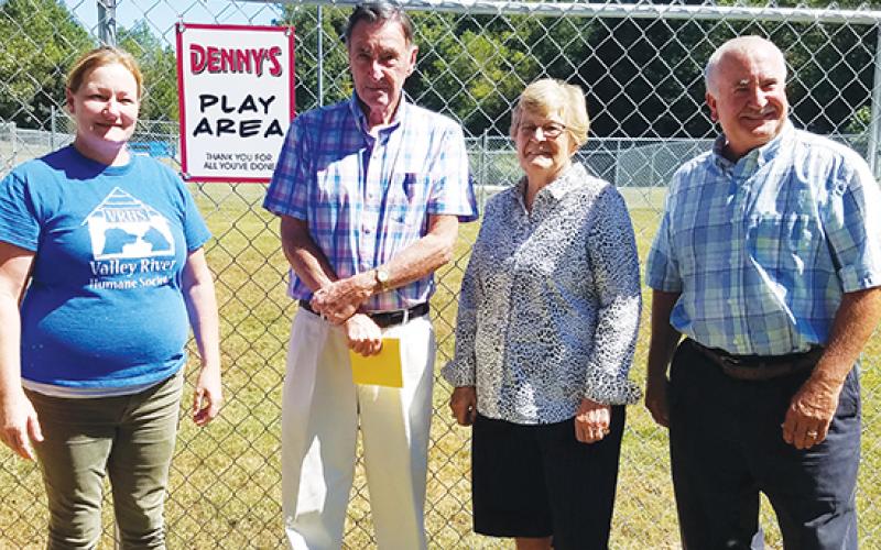 Animal shelter manager Kirsty Waller and Valley River Humane Society President Jeff Manson reveal the sign reading "Denny's Play Area" to its namesake, Denny Kendall, and his wife, Diane. 