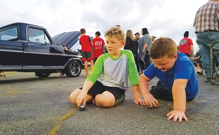 With the Mayor’s Choice-winning truck behind them, Braylen Guffie, 8, and Kip Beaver, 5, play with toy cars Saturday during Andrews Cruise Night for the Kids. 