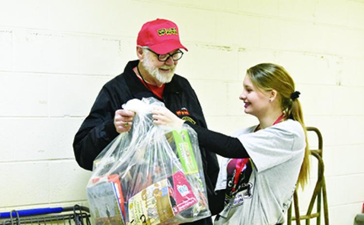 While volunteering at the Toys for Tots distribution, John Evans of Bellview is handed a bag of toys for a family by Jade Stiles. Photo by Samantha Sinclair