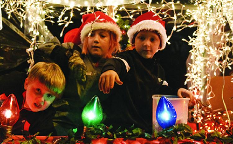 In their snow globe float, Cub Scouts Bradyn Thompson, Zack Bryant and Cale Wilson (from left) look for friends to throw candy to along the parade route Saturday night. Photo by Samantha Sinclair