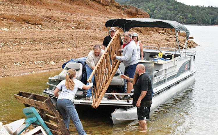 Noah Shatzer/sports@cherokeescout.com Mainspring Conservation Trust outreach associate Rachel Newcomb helps a pontoon boat of retired firefighters unload the trash they picked up around Hiwassee Lake.