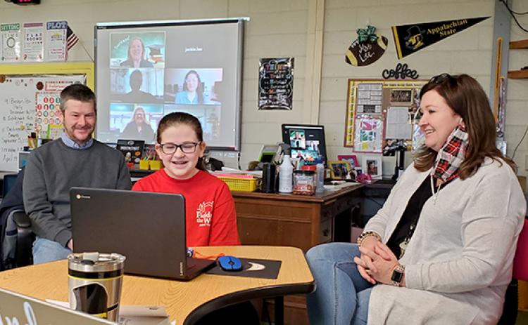Samantha Sinclair/scoutingaround@cherokeescout.com Abby Lee, with parents Tim and Jackie beside her, listens as College Foundation of North Carolina regional representative Devon McCarthy-James congratulates her during videoconference presentation Feb. 10. On the screen in the background are McCarthy-James, Hiwassee Dam Elementary/Middle School counselor Lauren Grubb, teacher Whitney Tanner and Principal Ruby Cutshaw.