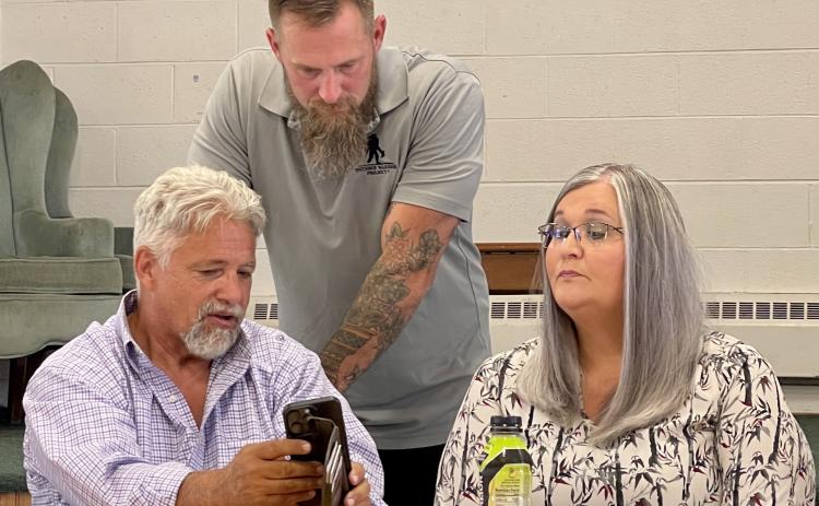 Andrews Mayor James Reid, Cherokee County school board member Steve Coleman and Andrews Mayor Pro Tem Brandi Smith hold a sidebar discussion following Coleman’s presentation of his school consolidation plan in Andrews on July 25.