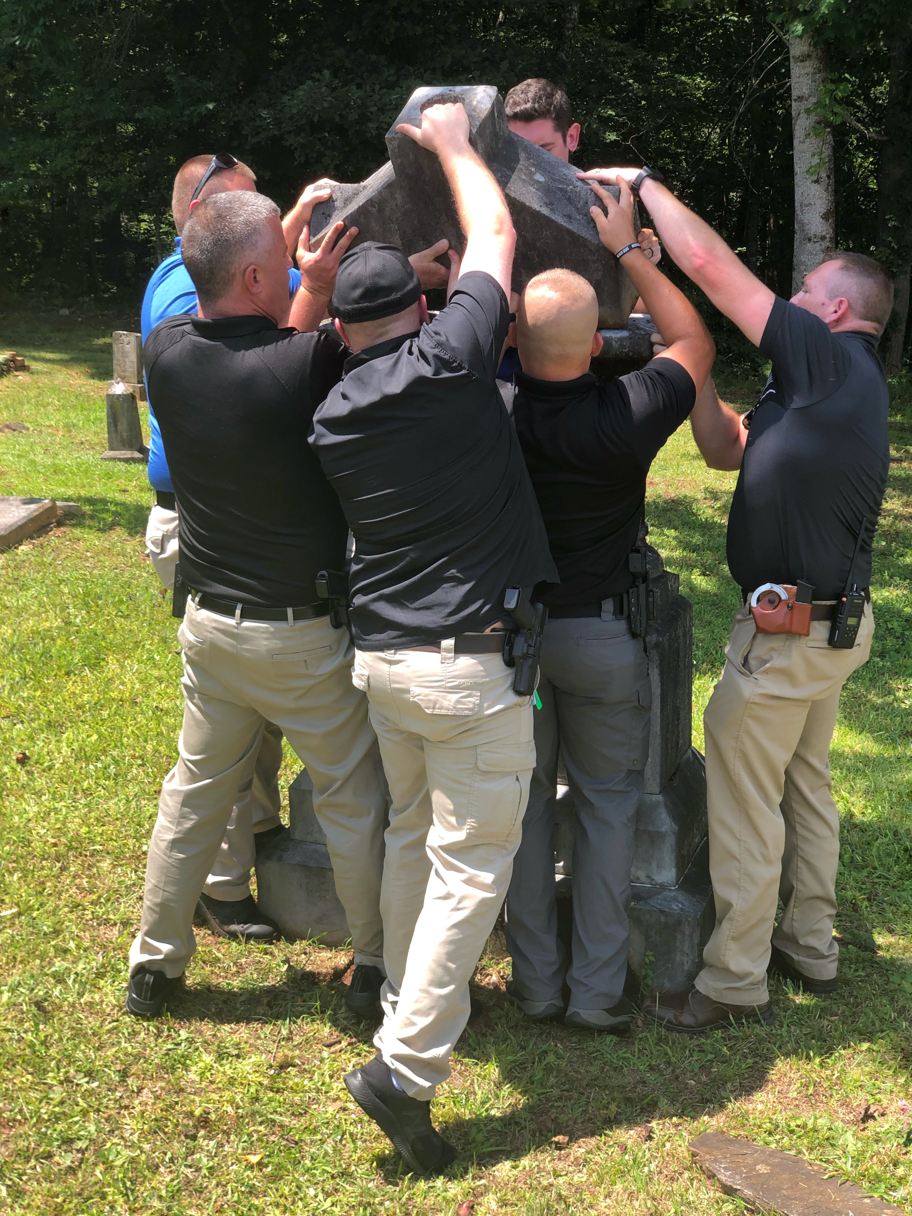 Officers from the Murphy Police Department and Cherokee County Sheriff’s Office re-erect gravestones that had been knocked down in Harshaw Cemetery.