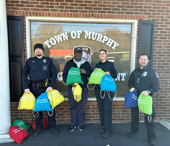 Ryan Cunningham/Contributing Photographer  The Murphy Police Department is helping deliver care packages to homeless people in the community. The brightly colored bags include items like blankets, caps, socks, a variety of toiletries and other items. The packages are given with compassion to help bring some comfort to those in need. Murphy police officers will be handing them out to folks they see needing a bit of extra care this Christmas season. The gift bags were put together by generous members of the Texana Community Development Club.&nbsp;From left are Cpl. Hunter Sanders, Texana Community Development Club President Eurial Turner, police Officer Mylie Sparks and Sgt. Adam May.