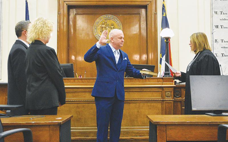 Photos by Randy Foster/editor@cherokeescout.com Chris Wood (center) swears on a Bible his oath of office administered by Superior Court Judge Tessa Sellers (right) with his wife Vivian (left) at the Cherokee County Courthouse on Monday morning.