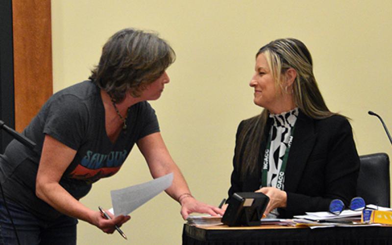 Randy Foster/editor@cherokeescout.com Cherokee County resident Katherine Taaffe (left) presents a petition to Maria Hass, clerk to the Cherokee County Board of Commissioners, calling for the county to protect public lands from private development at the Feb. 16 board of commissioners meeting.