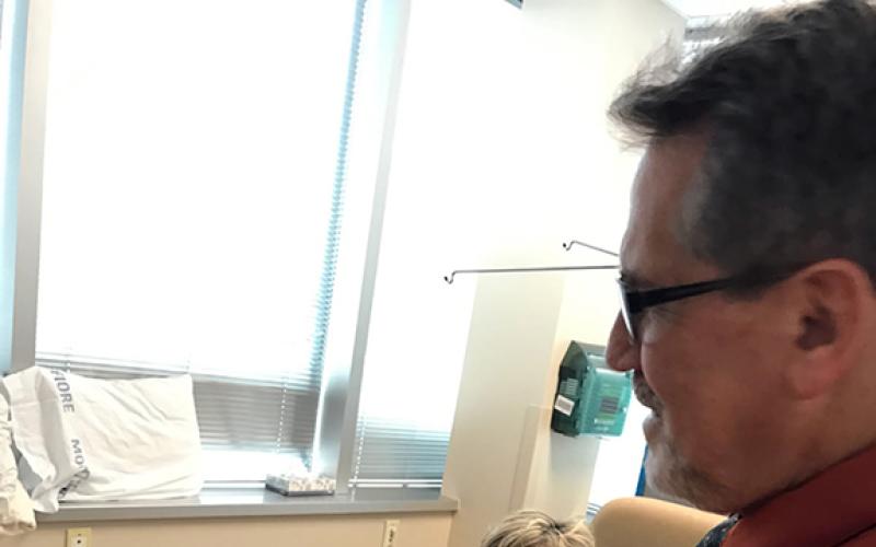 Debbie Sanders looks on as her doctor shows her husband how off-the-chart Debbie’s radiation levels were then.
