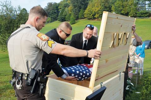 Members of the Cherokee County Sheriff’s Office place the remains of Deputy K-9 Ajax into a coffin that was buried at the law enforcement training center in Marble. Photos by Penny Ray