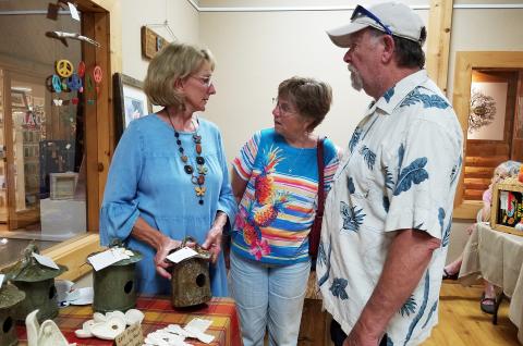 At the Fall into Art festival Friday during the Art Walk, Cathy Mozley tells Debbie and Jerry Cromer of Edisto Beach, S.C., about her ceramic bird houses.