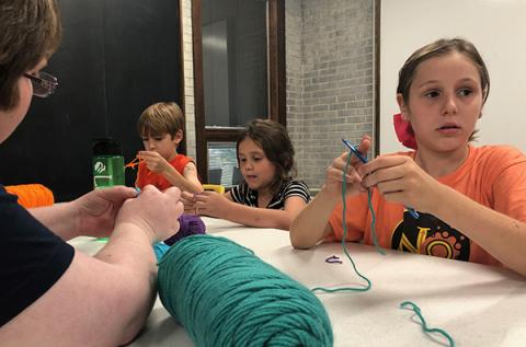 Zander Vaught, 8, Lacie Hall, 7, and Kimber Vaught, 9, learn crochet techniques taught by Bridget Wilson at the Andrews Public Library. 
