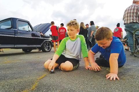 With the Mayor’s Choice-winning truck behind them, Braylen Guffie, 8, and Kip Beaver, 5, play with toy cars Saturday during Andrews Cruise Night for the Kids. 