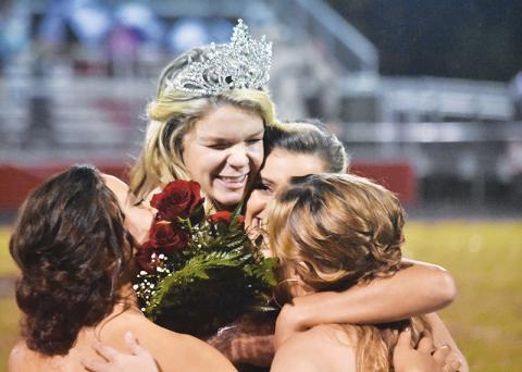 Andrews High School homecoming queen Juliana Aiken hugs fellow seniors (from left) Mariela Jimenez, Sydney Postell and Paige Hooper after getting her crown and roses Friday night.