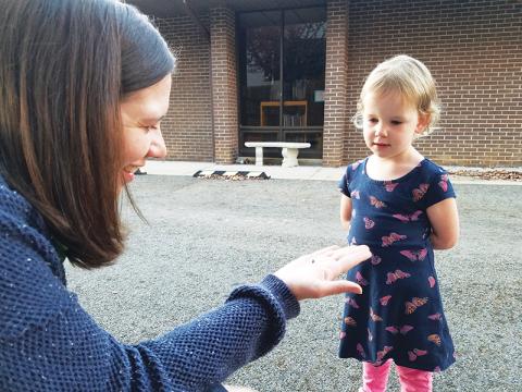 North Carolina Arboretum ecoExplore coordinator Libbie Dobbs-Alexander explains to 3-year-old Cora Dance of Murphy that the bug she found on the library grounds is a ladybug larva.