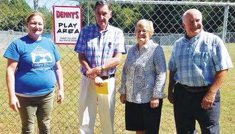 Animal shelter manager Kirsty Waller and Valley River Humane Society President Jeff Manson reveal the sign reading "Denny's Play Area" to its namesake, Denny Kendall, and his wife, Diane. 