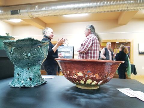 The “Fashioned in the Clay” show displays a variety of items, from practical to decorative, including Lisa Proper’s intricate fruit and centerpiece bowls. In the background, Elo-ly Bailey, David Vowell, Kathy Ross and Proper hold conversations during the exhibit’s opening.