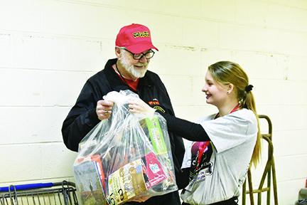 While volunteering at the Toys for Tots distribution, John Evans of Bellview is handed a bag of toys for a family by Jade Stiles. Photo by Samantha Sinclair