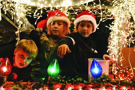 In their snow globe float, Cub Scouts Bradyn Thompson, Zack Bryant and Cale Wilson (from left) look for friends to throw candy to along the parade route Saturday night. Photo by Samantha Sinclair