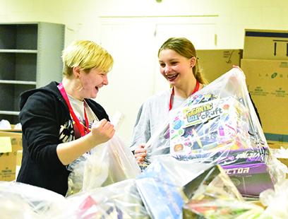 Tri-County Early College High School students Marie Townson and Jade Stiles carry bags of toys they gathered for a family during Toys for Tots distribution Dec. 13. Photo by Samantha Sinclair