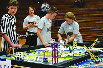 As teammates Paige Black and Lyden Raxter watch and assist, Cece Ward makes adjustments her team’s robot during Murphy Middle School’s final robot performance run in the FIRST Lego League robotics qualifying tournament on Nov. 23 in Blairsville, Ga. Photo by Samantha Sinclair