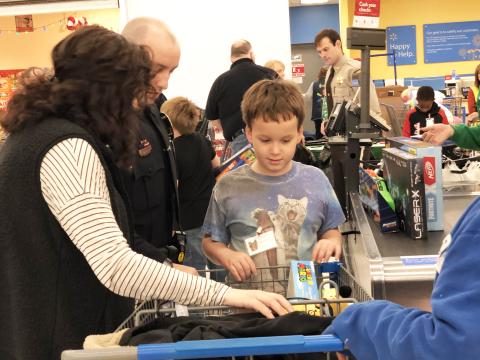Zachary Gent admires the basket full of toys he picked out during Shop With a Cop on Saturday morning at Walmart in Murphy. Photo by Penny Ray.