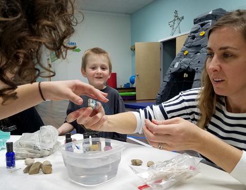 Alex Flaws watches in wonder as Maddy Lincoln teaches him and Elizabeth Ference how to marbleize a rock. Photo by Samantha Sinclair
