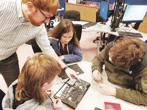 David Decker coaches eighth-grade students Tommy Crapse, Carly Pope and Andrew Thompson on what steps to take to repair a Chromebook on the morning of Jan. 28. Photo by Samantha Sinclair
