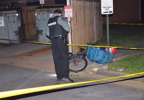 Police examine the area where Charles McTaggart struggled with his killer next to a Dumpster at the Andrews Housing Authority. Photo by Penny Ray