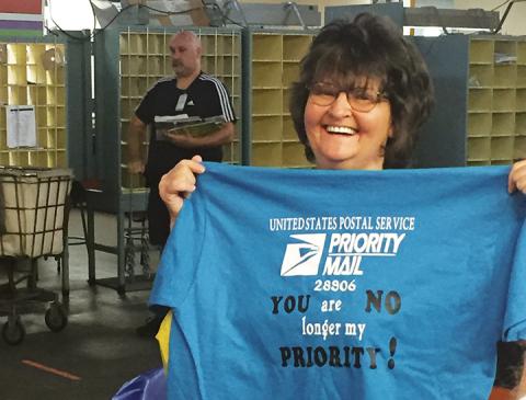 Ava Anderson holds up a shirt she received during her retirement party at the Murphy Post Office.