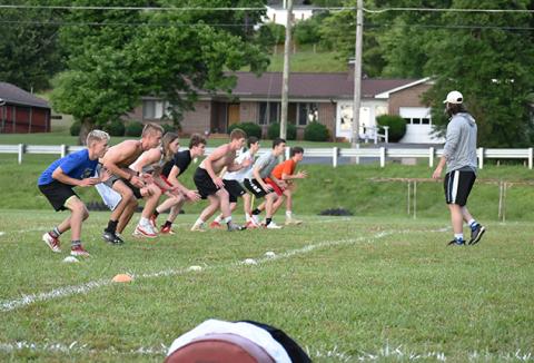 Andrews football assistant Matthew Maennle runs the Wildcats defensive backs (spaced 6 feet apart) through coverage drills during workouts on June 16. Photo by Noah Shatzer