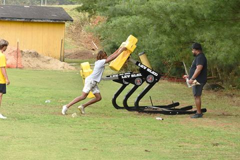 Murphy High School defensive coordinator Thomas Nelson, with a spray bottle of sanitizer and rag at the ready,  watches defensive back Juan Allen go through sled drills during one of the Bulldogs’ off-season workouts. 