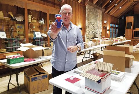 As crafts wait in the Keith House to be packed for delivery, Executive Director Jerry Jackson shows a blue felt bear donated to the Hearts at Work project that will remain on the John C. Campbell Folk School campus as a protector. Photo by Samantha Sinclair