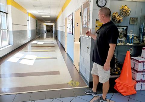 Murphy Elementary School Principal Dane Rickett shows decals placed on the floors to remind children to maintain 6 feet of distance. Children were told to not walk in the center of the hallway within the yellow stripes. Photo by Samantha Sinclair
