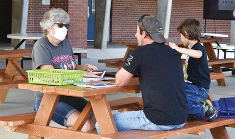 Samantha Sinclair/scoutingaround@cherokeescout.com First-grade teacher Regina Mashburn goes over assignments with Tim Anderson and his son, Gavin, on the morning of Sept. 16 in Hiwassee Dam’s outdoor classroom.