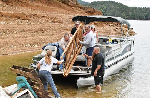 Noah Shatzer/sports@cherokeescout.com Mainspring Conservation Trust outreach associate Rachel Newcomb helps a pontoon boat of retired firefighters unload the trash they picked up around Hiwassee Lake.