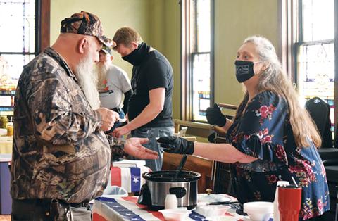 Samantha Sinclair/scoutingaround@cherokeescout.com Margaret Phillips hands a sample of her chili to a taster at the third annual Fire in the Valley chili cook-off Saturday.