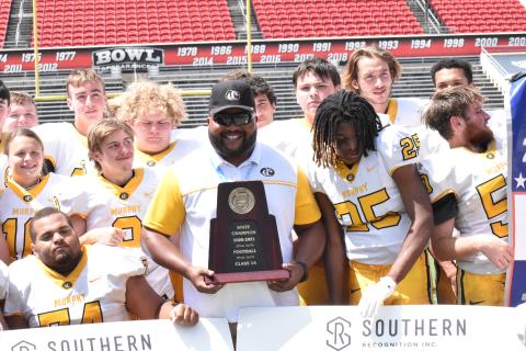 Justin Fitzgerald/sports@cherokeescout.com Murphy defensive coordinator Thomas Nelson smiles with the state championship trophy after the Bulldogs’ 14-7 win over Northside-Pinetown on May 8. Nelson is leaving Murphy and starting a new job at Union County High School in nearby Blairsville, Ga., this fall.