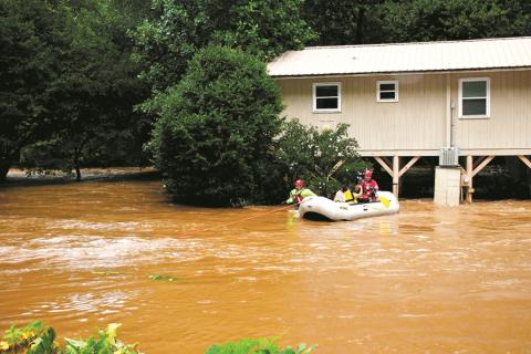 Clay County Swift Water Rescue team members Tim Noland and Henry Angelopulos take an unidentified woman from her Brasstown home, which was surrounded by flood water, to the safety of dry ground on Aug. 17.