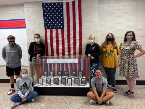 From left, Elijah Mayfield, Mandy Pendergrass, Kinleigh Queen, Americas LeQuire, Kaylin Ellis, Macie Postell and history teacher Nicole Hedden next to a memorial in honor of the 13 service members killed in Kabul last month. Students who helped with the exhibit but not pictured are Makayla Whitehead, Michael Samten, Madison Cogdill, Marlee Postell, Bronson Ludixen, Brianna Downs and O'Ryan Brockwell.