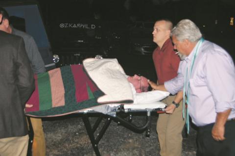Tim Radford on a stretcher assisted by Murphy police Investigator Jason Murphy and Andrews Mayor James Reid.