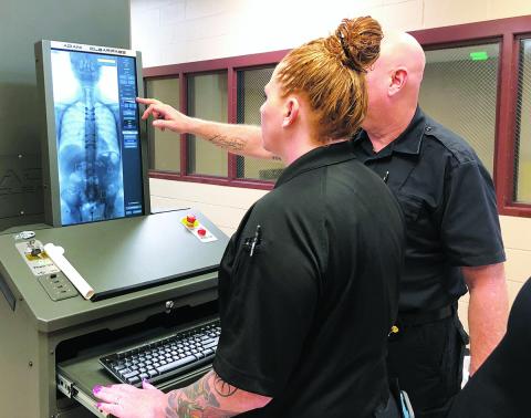 Cherokee County Detention Center staff demonstrate a new security scanner that can detect drugs and contraband hidden within body cavities. 