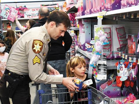 Sgt. T.J. Major with the Cherokee County Sheriff’s Office shops with Amrie Chapman during the annual Shop With a Cop event Saturday morning at Walmart in Murphy. Almost 100 children in grades K-5 received a $150 gift card, breakfast, lunch and a bus ride complete with blue sirens at full volume. Photos by Bill Belian/ Contributing Photographer