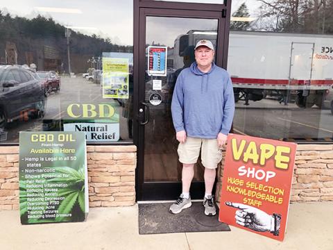 Abigail Hickman/Staff Correspondent Faithful employee Jason Smith stands next to a small sign on his door stating, “No one under 21 admitted,” outside the Vape shop on U.S. 64 West in Murphy.