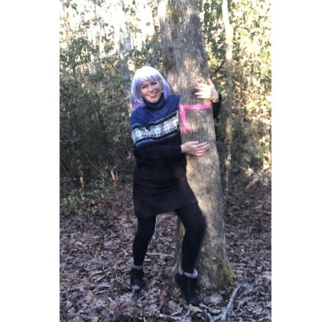 Abigail Hickman hugging the marked tree that stands on the wrong side of her property line in Murphy.
