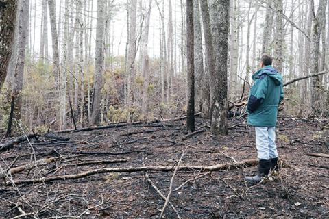 Jared Putnam/editor@cherokeescout.com Richard Foster stands on a portion of his county land charred by a February brush fire that started when manmade materials were burned on a neighboring property.