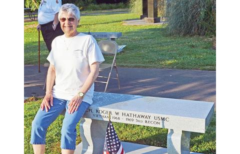 Abigail Hickman/Staff Correspondent Gwen Hathaway rests on the memorial bench honoring her late husband, Cpl. Roger Hathaway, at the Konehete Park Memorial Day wreath ceremony Monday morning. 