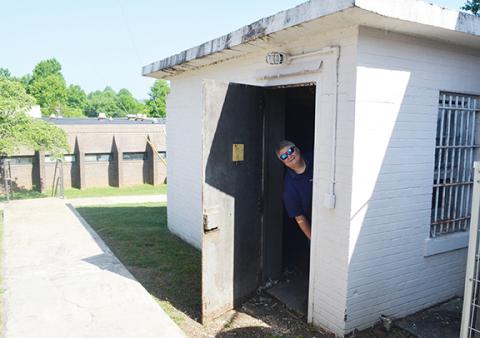 Trevis Hicks peeks out from the solitary confinement house on the Tri-County Community College campus.