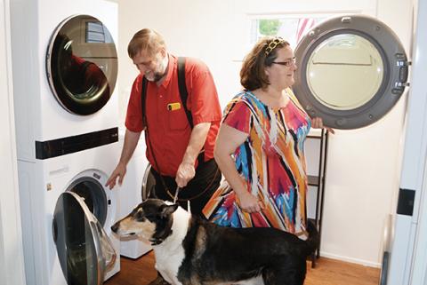 Pastor Tim Huff examines the new industrial washers and dryers at the Hurlburt Johnson Friendship House homeless shelter in Murphy along with house manager Peggy White and Huff’s curious dog, Gus.